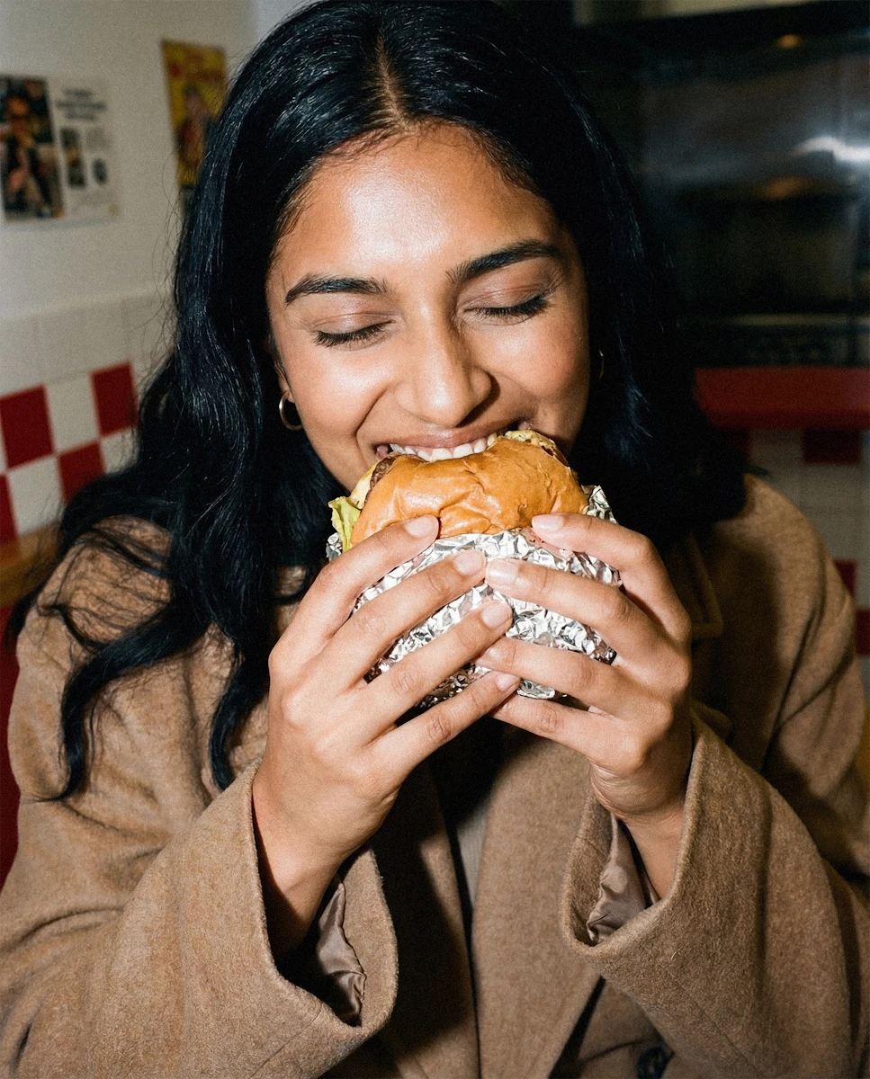 A woman biting into a burger, eyes closed